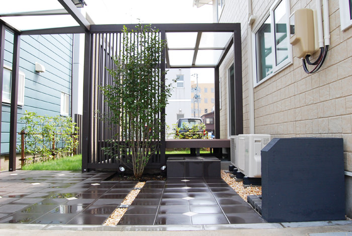 縦格子の前にも植栽を植えてナチュラルテイストを前面に出しています。シンボルツリーとして植えた高木なので、夜は一層素敵に見えるよう下部にスポットライトを2機取り付けました。 《新築エクステリア工事写真集》-進藤様邸-10